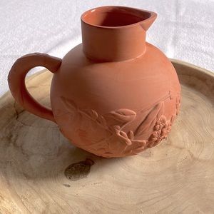 Terracotta pitcher with embossed flowers.